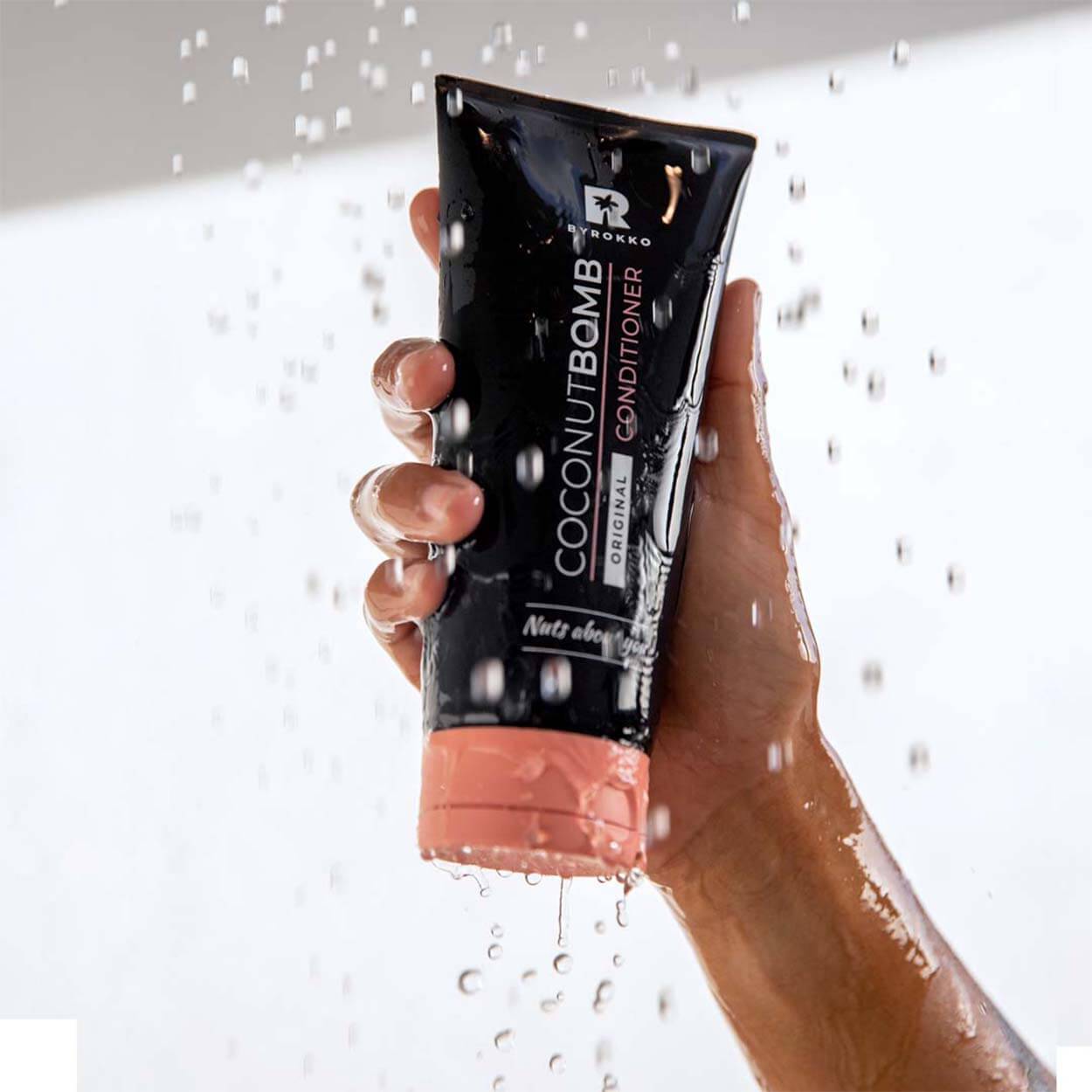 Byrokko Coconut Bomb conditioner in the woman's hands with drops of water.