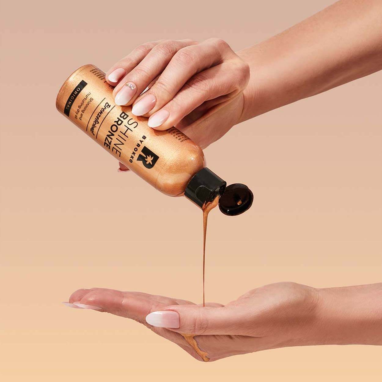 A girl is applying Shine Bronze shinning and nurturing dry oil on her hands.