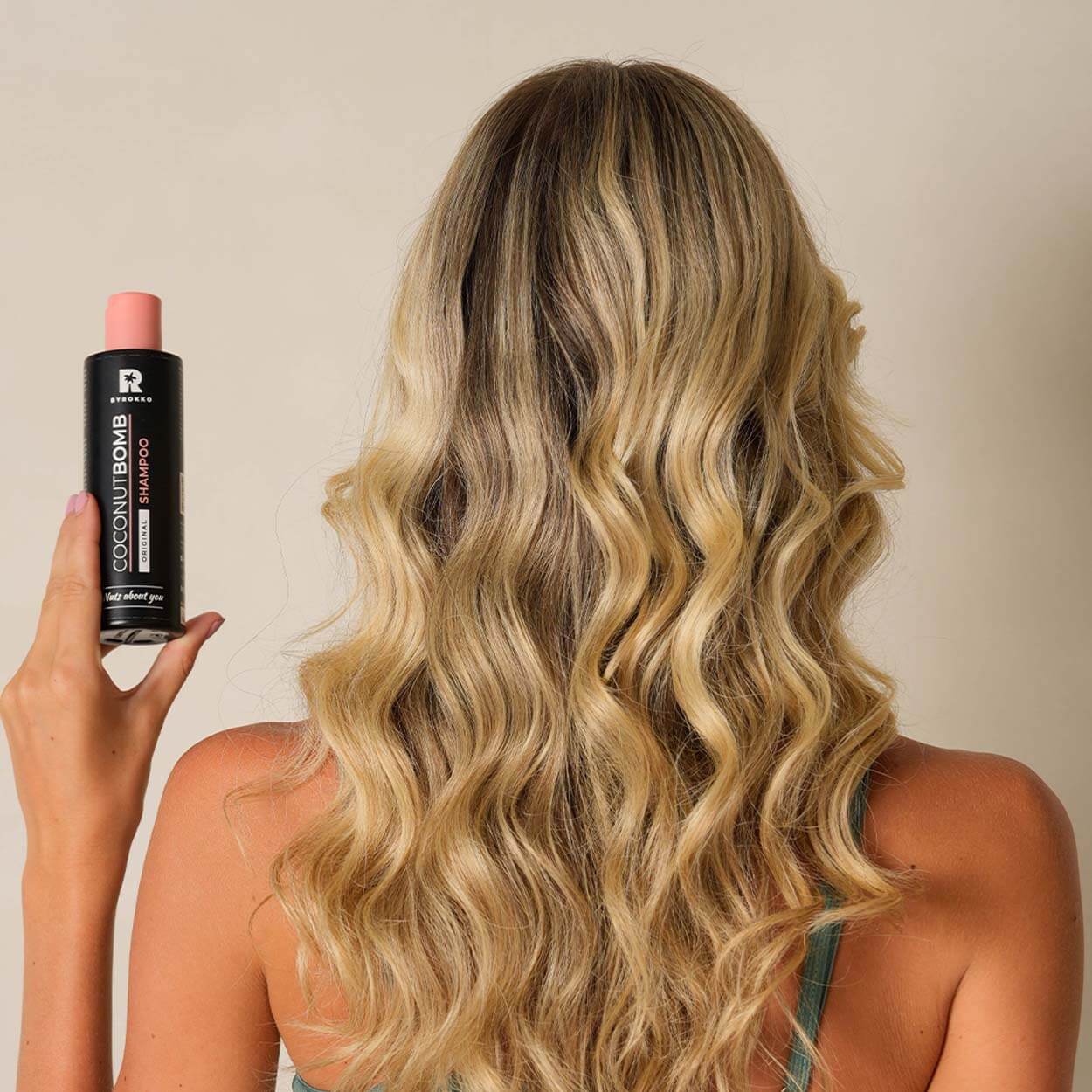 Byrokko Coconut Bomb shampoo is in the hands of a girl with wavy blond hair.