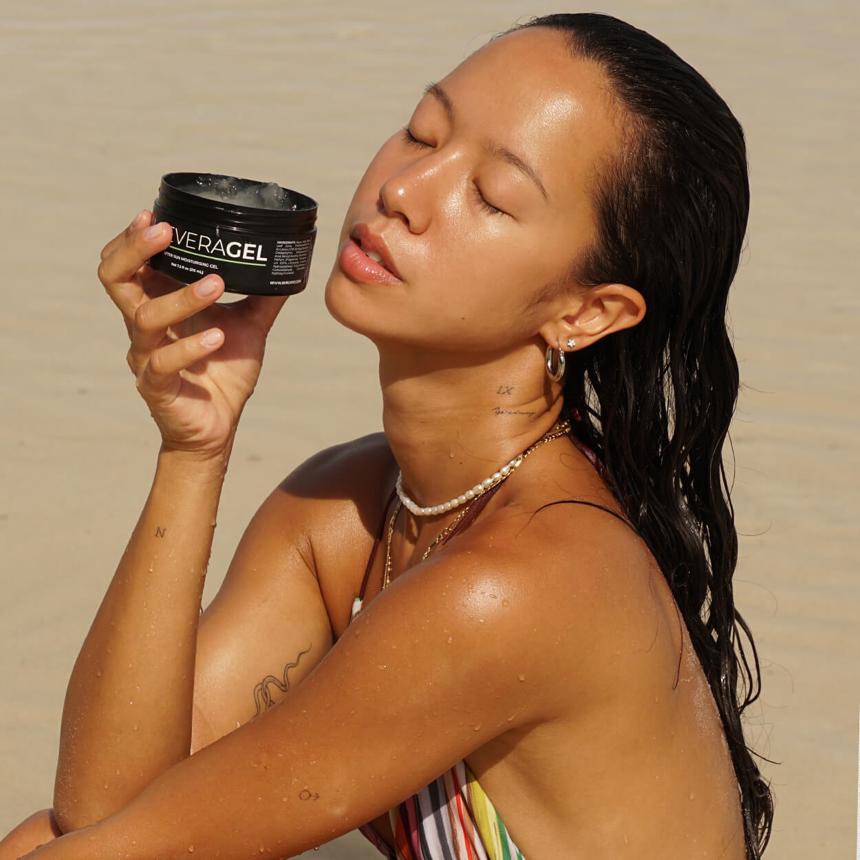 An opened package of Byrokko aloe vera gel, is in the hands of a brunette girl, with wet hair.